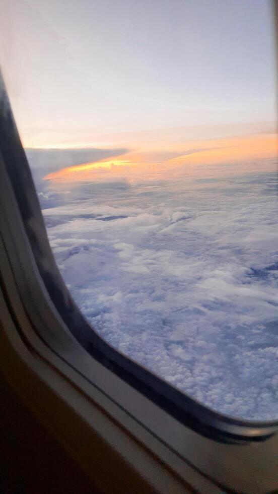 vista desde la ventana del avión. el cielo con nubes blancas y fondo azul. tiempo despejado con una luz de sol que se hunde y revela las alas del avión foto