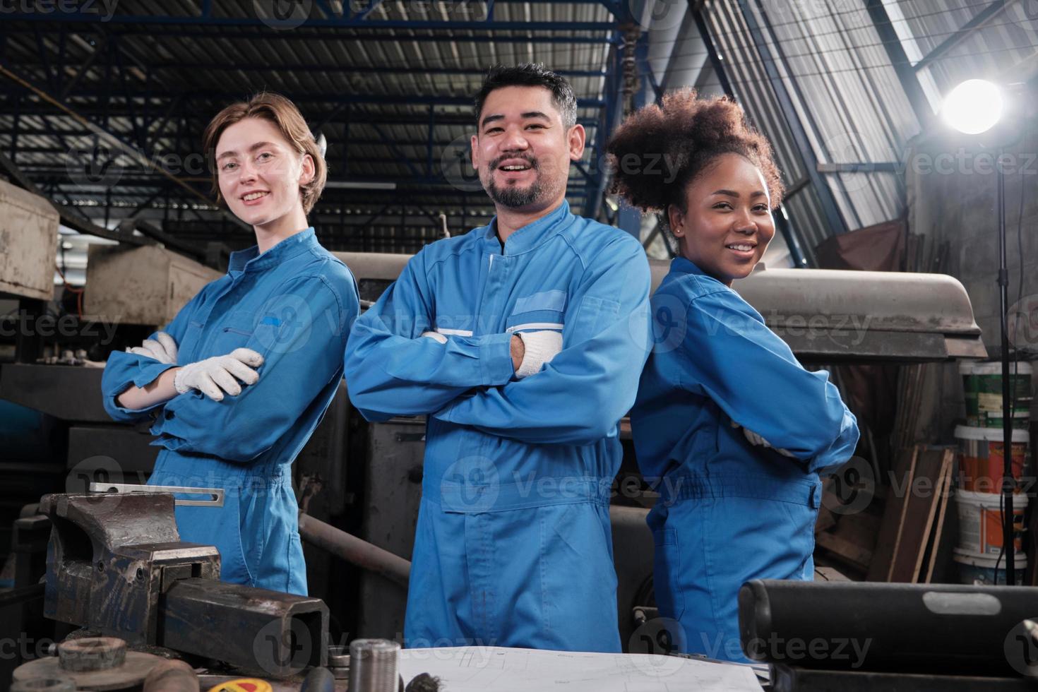 los trabajadores de la industria multirracial con uniformes de seguridad colaboran con unidad, se cruzan de brazos y expresan un trabajo feliz junto con una sonrisa y alegría en la fábrica mecánica, ocupación de ingeniero profesional. foto