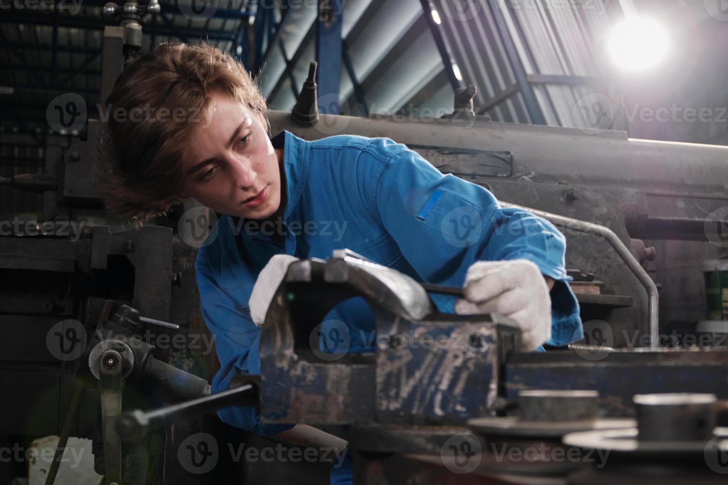 One professional young female industry engineer worker works in a safety uniform with metalwork precision tools, mechanical lathe machines, and spare parts workshop in the steel manufacturing factory. photo