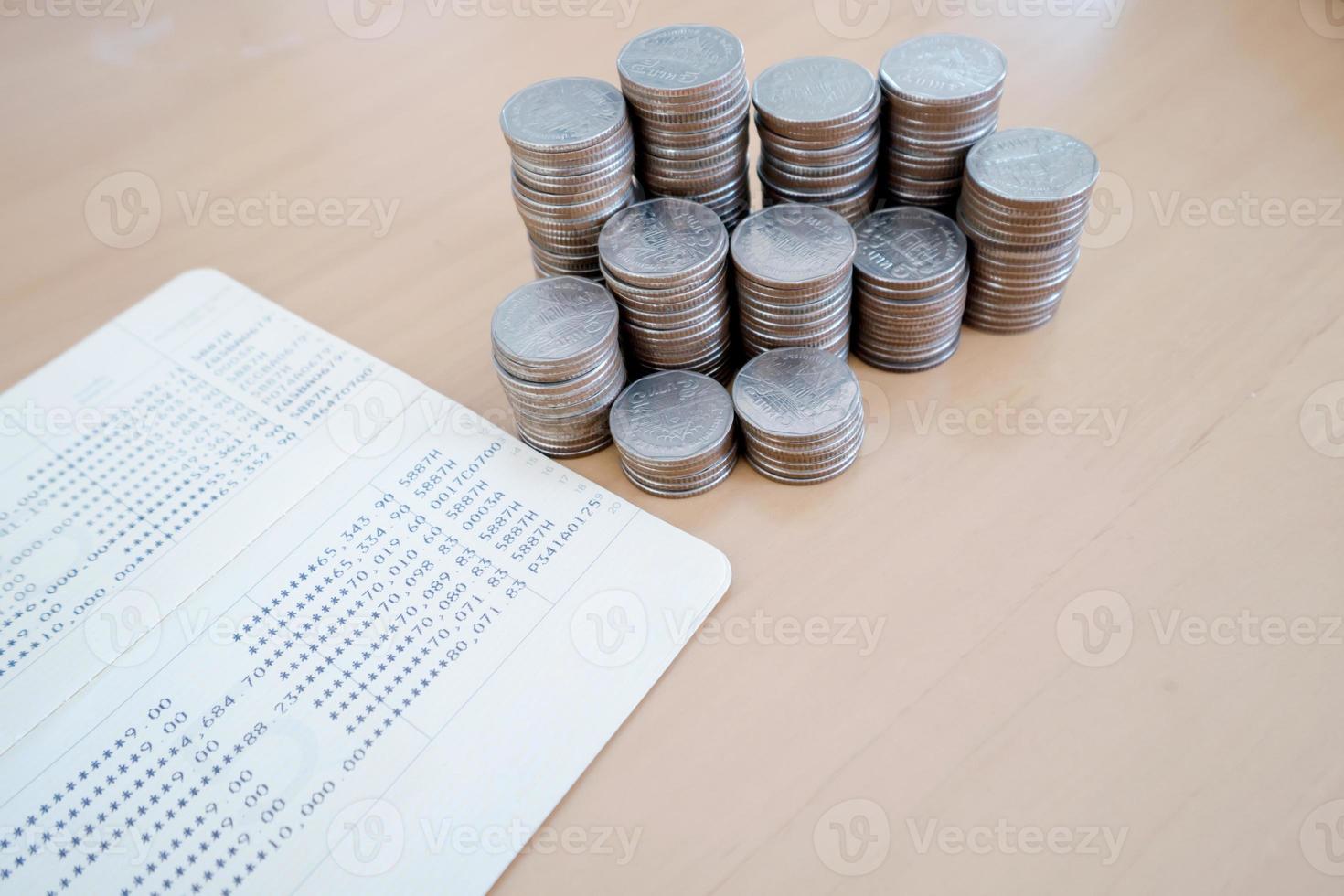 ahorrar dinero con pila de monedas y libreta en mesa de madera foto