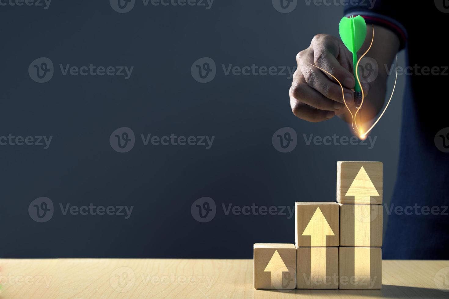 Hand putting bullseye on wooden cubes block which print screen increase or up white arrow photo