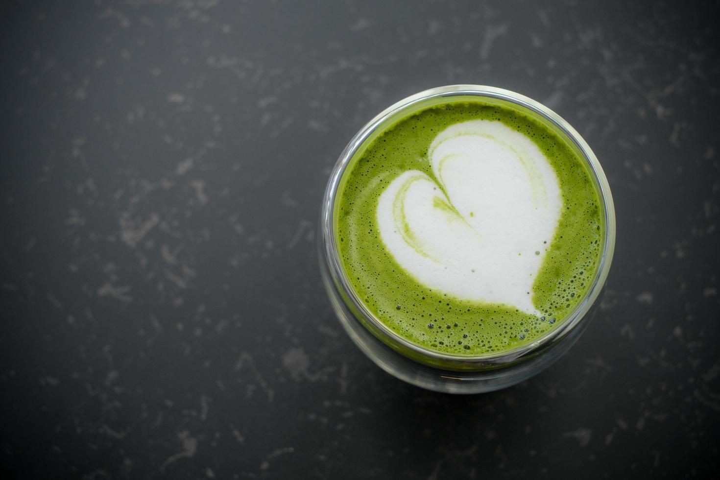 Top view of hot matcha green tea latte art in double walled glass on table in the cafe. Flat lay. photo