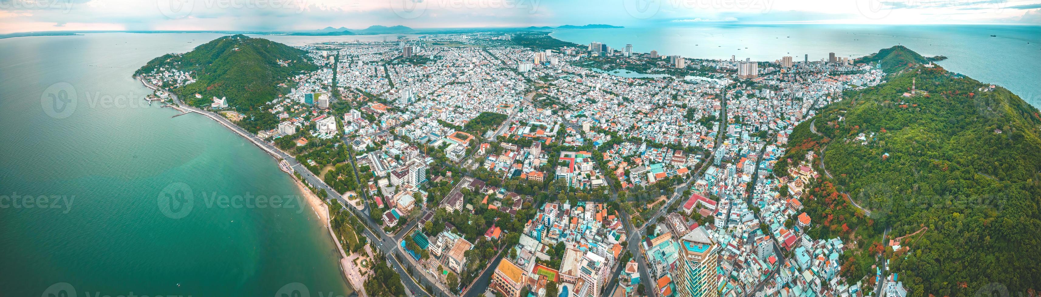 Vung Tau city aerial view with beautiful sunset and so many boats. Panoramic coastal Vung Tau view from above, with waves, coastline, streets, coconut trees and Tao Phung mountain in Vietnam. photo