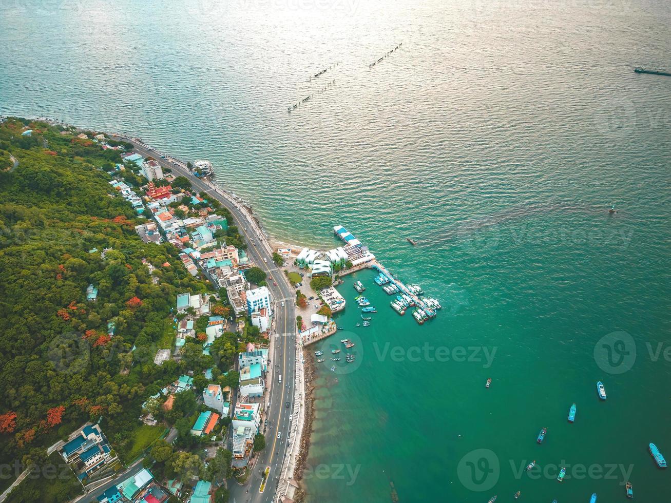 Vung Tau city aerial view with beautiful sunset and so many boats. Panoramic coastal Vung Tau view from above, with waves, coastline, streets, coconut trees and Tao Phung mountain in Vietnam. photo