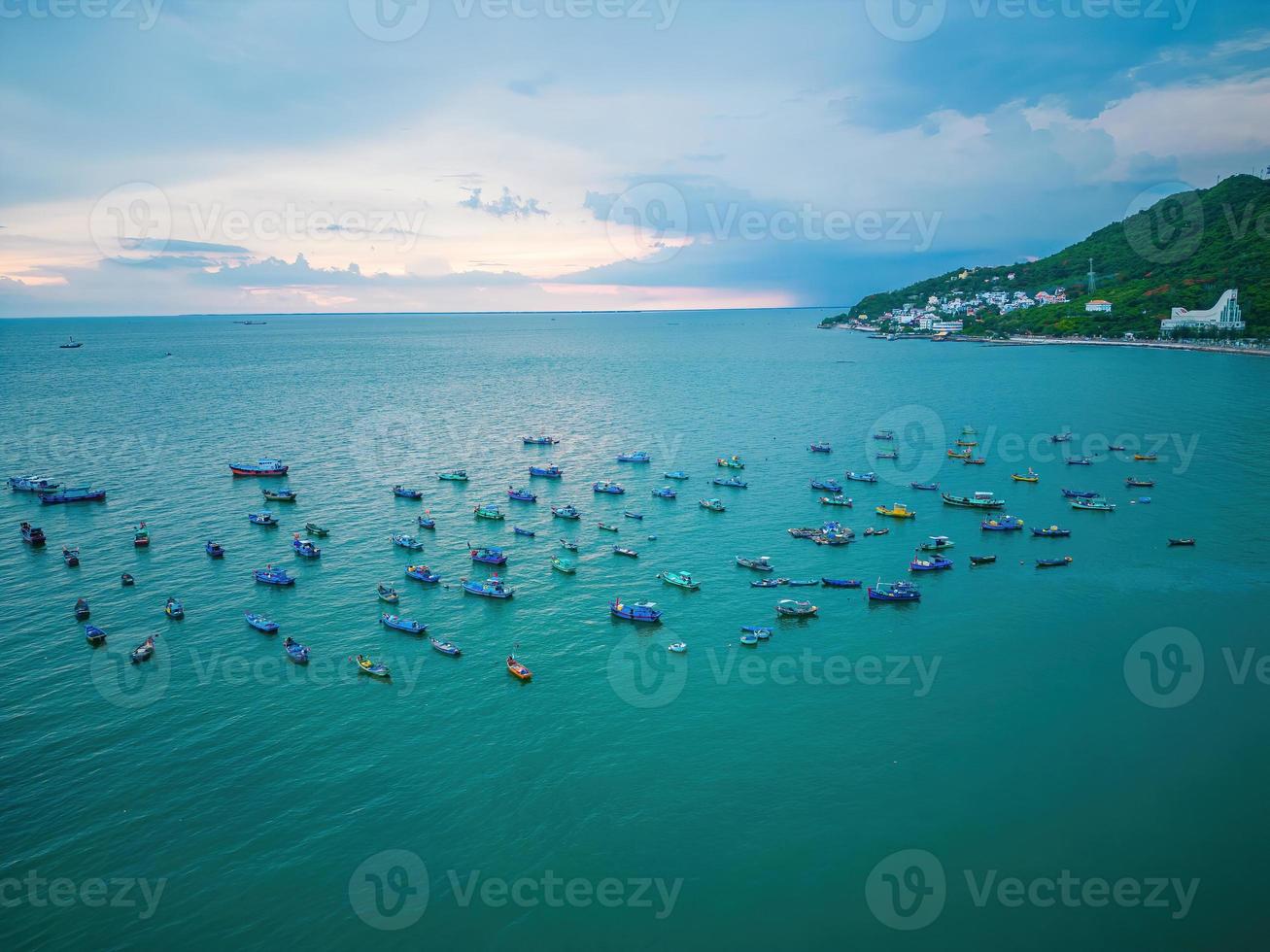 Vung Tau city aerial view with beautiful sunset and so many boats. Panoramic coastal Vung Tau view from above, with waves, coastline, streets, coconut trees and Tao Phung mountain in Vietnam. photo