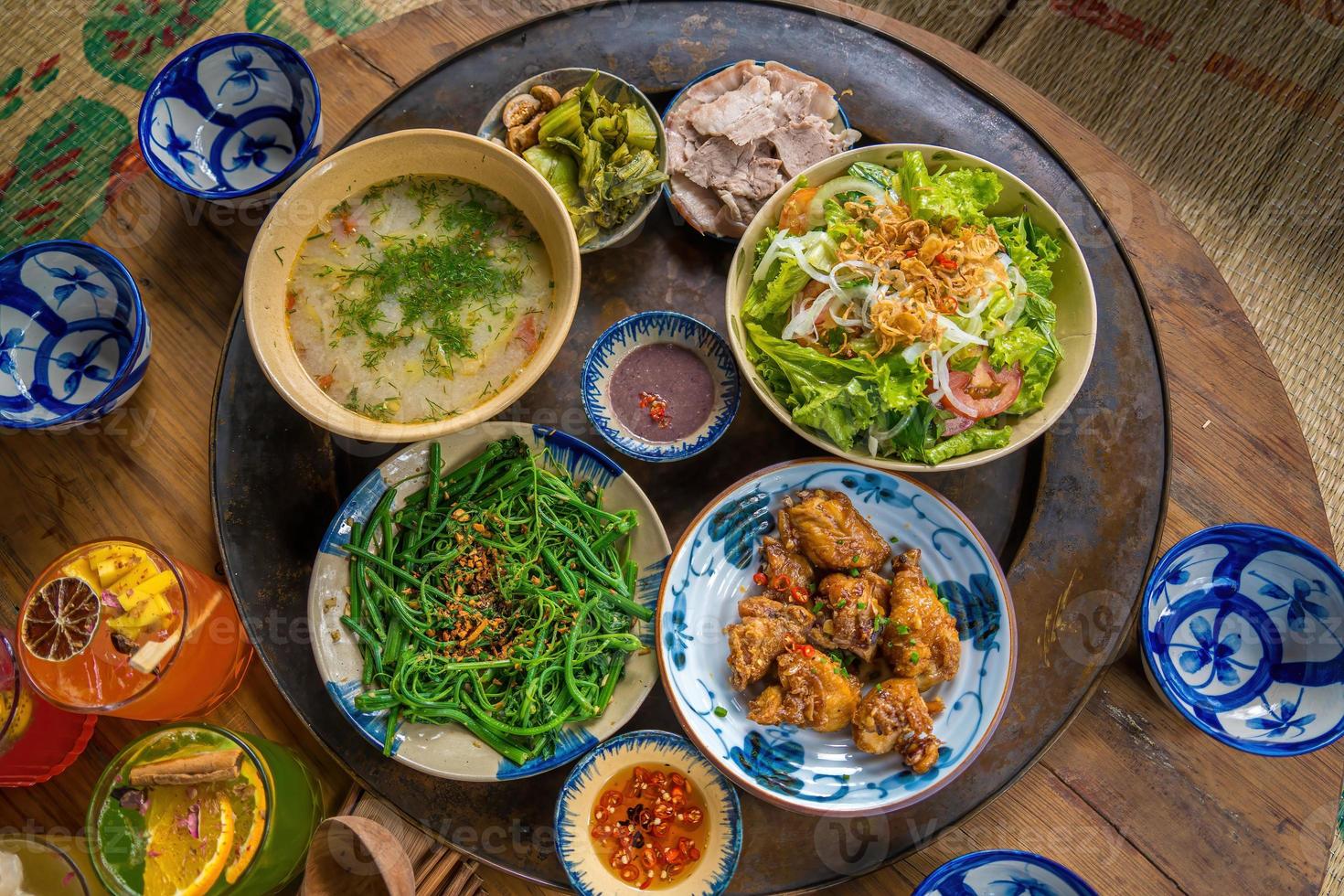 cocina casera de la familia vietnam preparada para cuatro personas arroz cocido, sopa de verduras y pescado frito, cebollas fritas con pollo, rodaja de pepino, comida tradicional vietnamita en el campo. foto