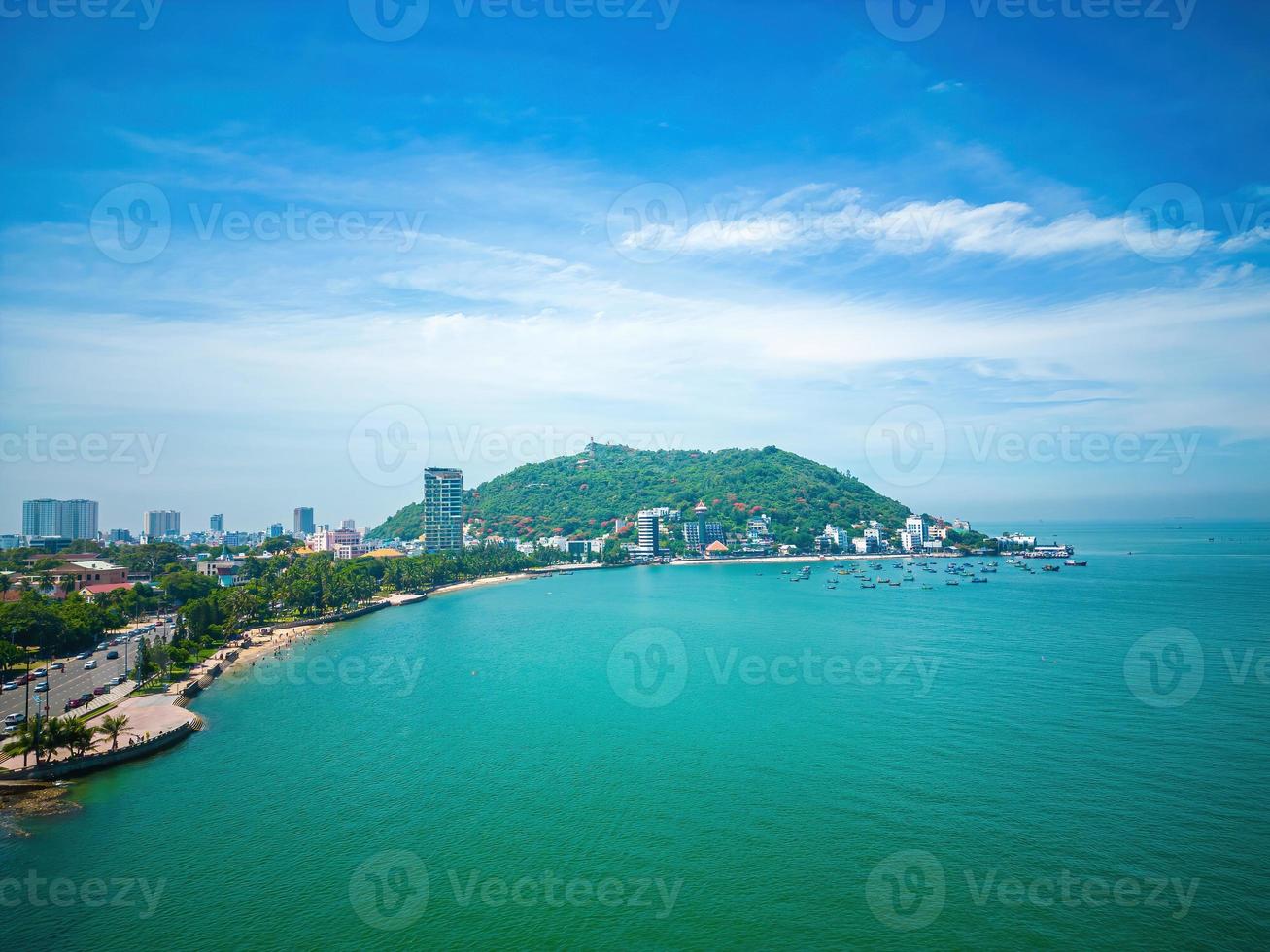 Vung Tau city aerial view with beautiful sunset and so many boats. Panoramic coastal Vung Tau view from above, with waves, coastline, streets, coconut trees and Tao Phung mountain in Vietnam. photo