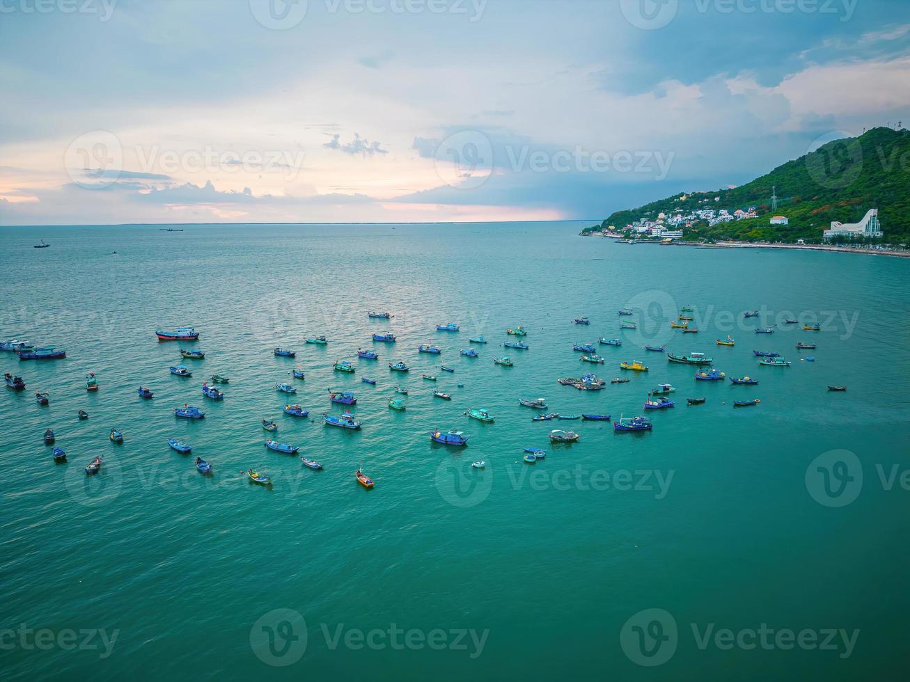 Vung Tau city aerial view with beautiful sunset and so many boats. Panoramic coastal Vung Tau view from above, with waves, coastline, streets, coconut trees and Tao Phung mountain in Vietnam. photo