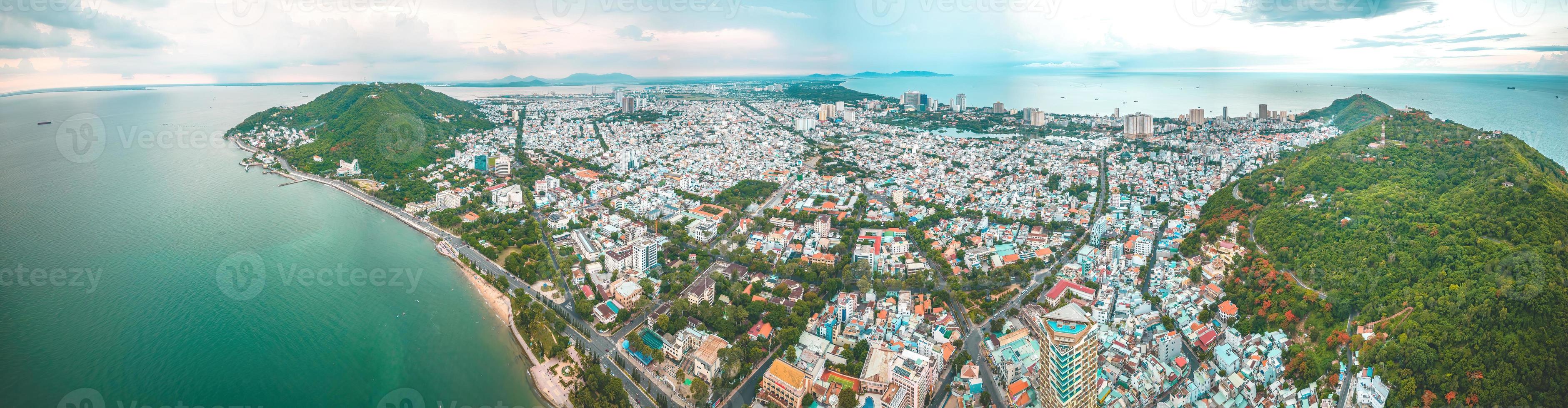 Vung Tau city aerial view with beautiful sunset and so many boats. Panoramic coastal Vung Tau view from above, with waves, coastline, streets, coconut trees and Tao Phung mountain in Vietnam. photo