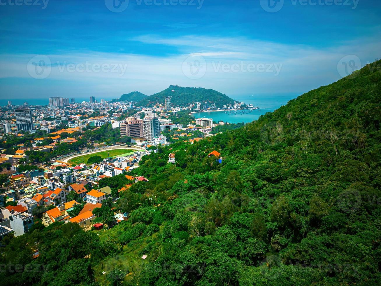 Vung Tau city aerial view with beautiful sunset and so many boats. Panoramic coastal Vung Tau view from above, with waves, coastline, streets, coconut trees and Tao Phung mountain in Vietnam. photo