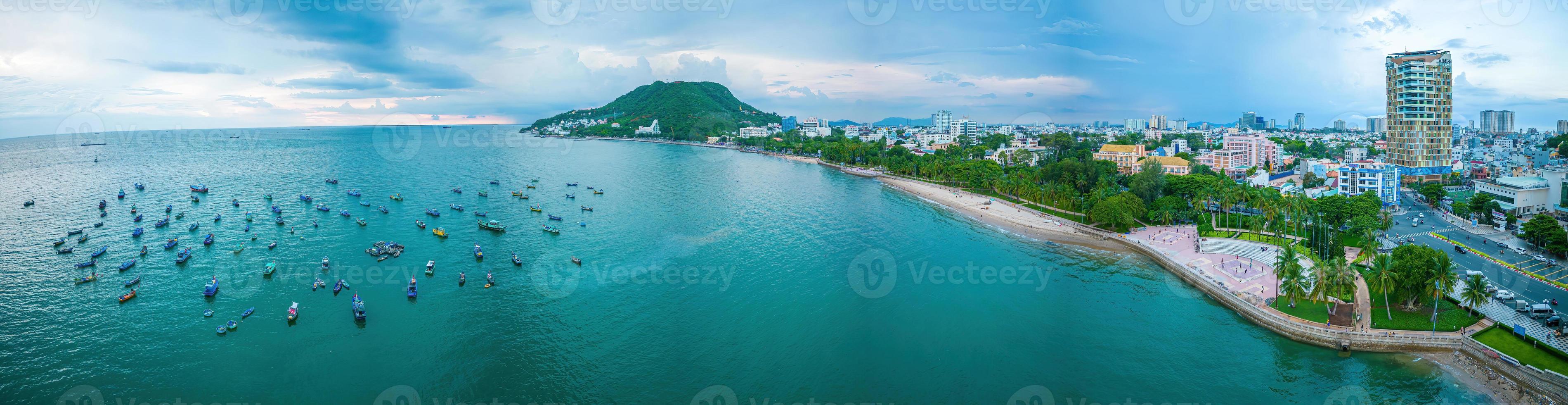 Vung Tau city aerial view with beautiful sunset and so many boats. Panoramic coastal Vung Tau view from above, with waves, coastline, streets, coconut trees and Tao Phung mountain in Vietnam. photo