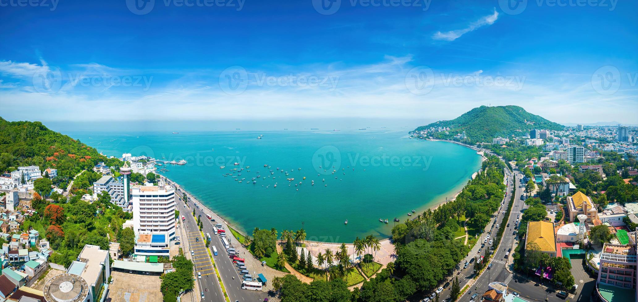 Vung Tau city aerial view with beautiful sunset and so many boats. Panoramic coastal Vung Tau view from above, with waves, coastline, streets, coconut trees and Tao Phung mountain in Vietnam. photo
