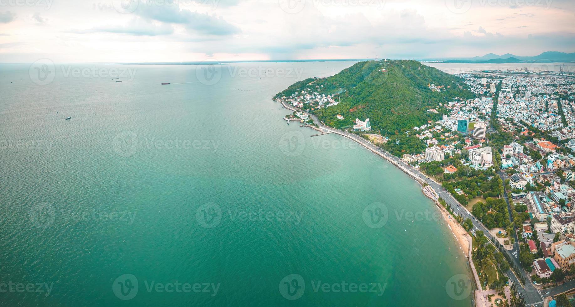 Vung Tau city aerial view with beautiful sunset and so many boats. Panoramic coastal Vung Tau view from above, with waves, coastline, streets, coconut trees and Tao Phung mountain in Vietnam. photo