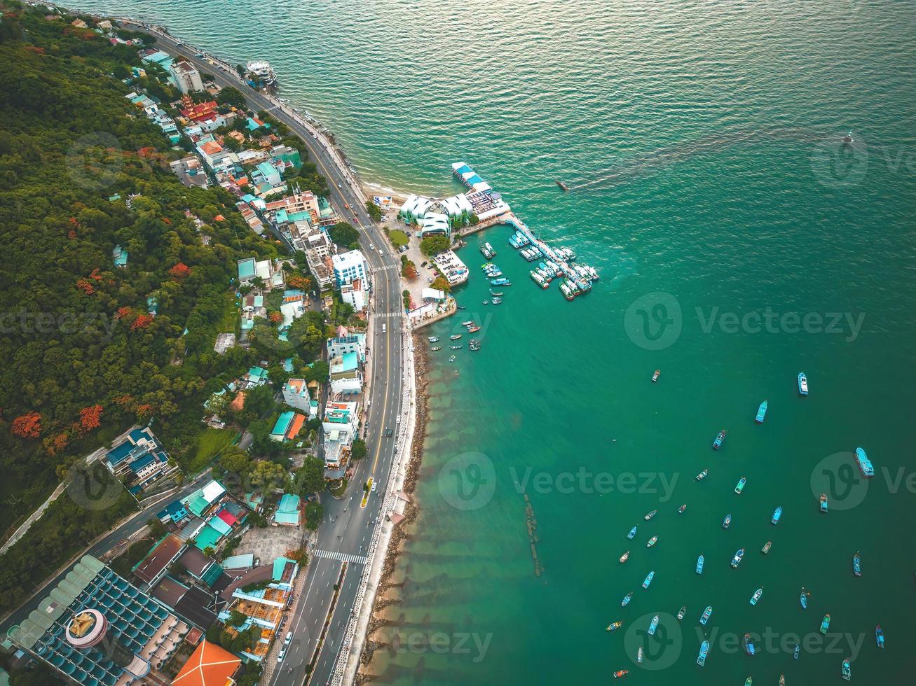 Vung Tau city aerial view with beautiful sunset and so many boats. Panoramic coastal Vung Tau view from above, with waves, coastline, streets, coconut trees and Tao Phung mountain in Vietnam. photo