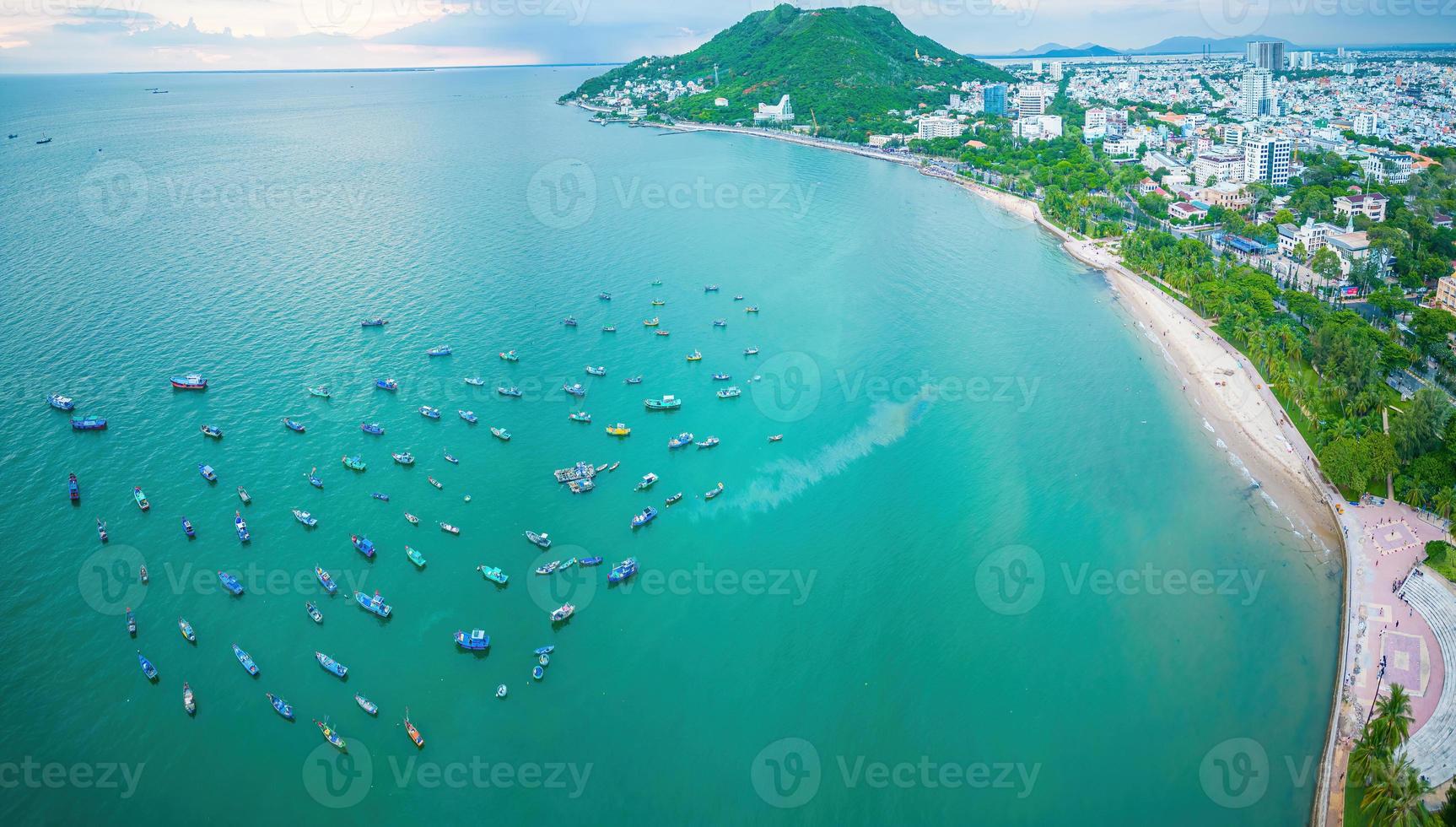 Vung Tau city aerial view with beautiful sunset and so many boats. Panoramic coastal Vung Tau view from above, with waves, coastline, streets, coconut trees and Tao Phung mountain in Vietnam. photo