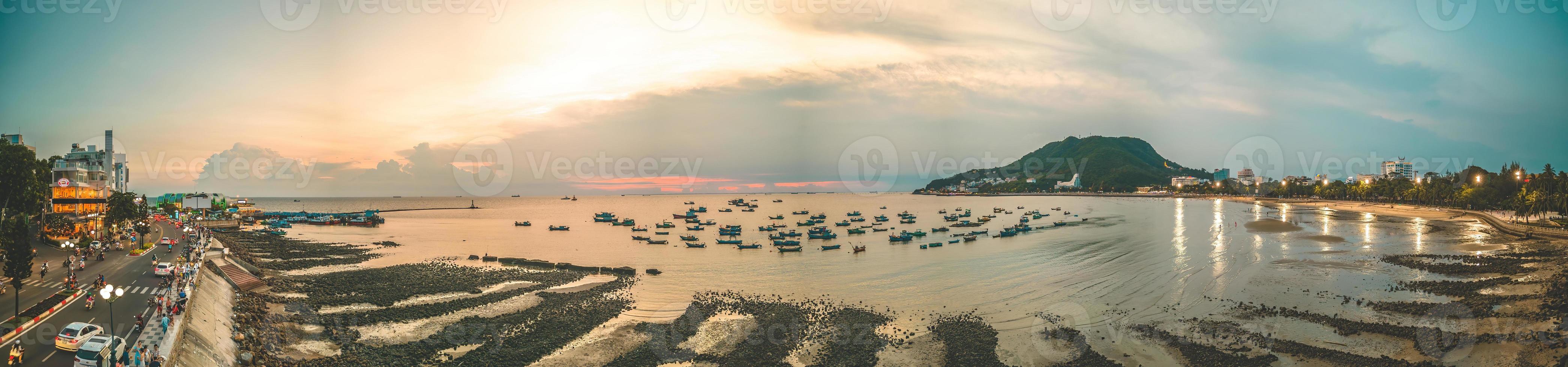 Vung Tau city aerial view with beautiful sunset and so many boats. Panoramic coastal Vung Tau view from above, with waves, coastline, streets, coconut trees and Tao Phung mountain in Vietnam. photo