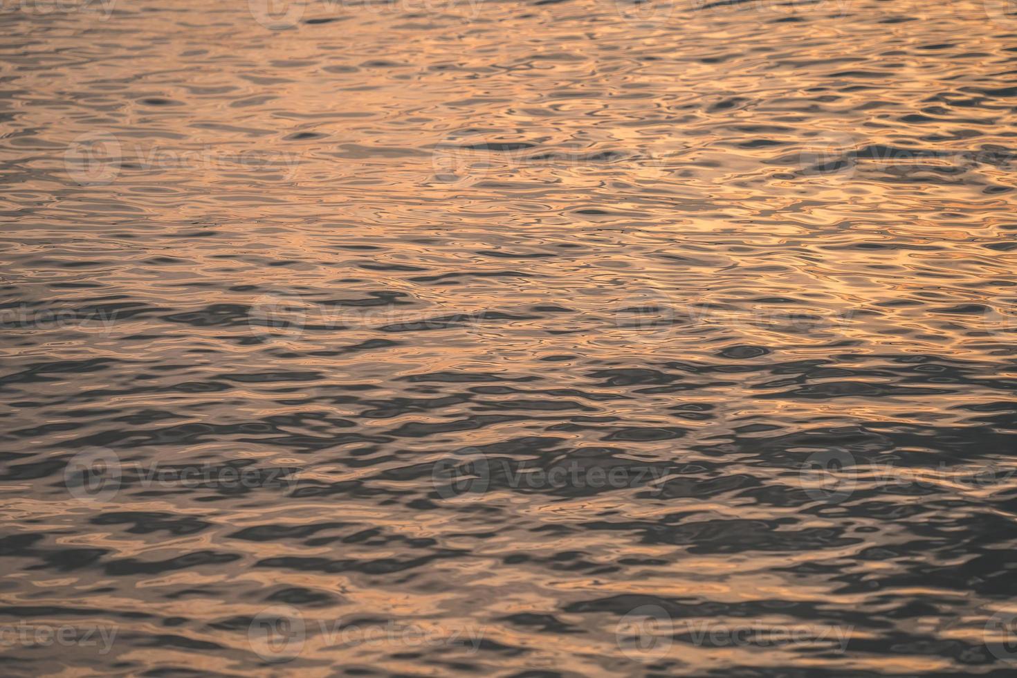 Sunset water reflect ripples at sun light. Abstract golden reflection on water sunset photo