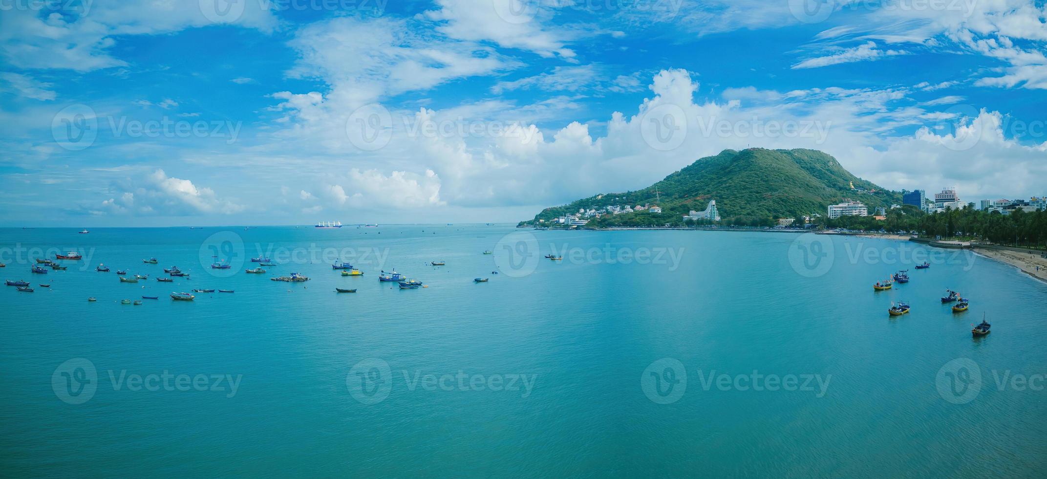 Vung Tau city aerial view with beautiful sunset and so many boats. Panoramic coastal Vung Tau view from above, with waves, coastline, streets, coconut trees and Tao Phung mountain in Vietnam. photo