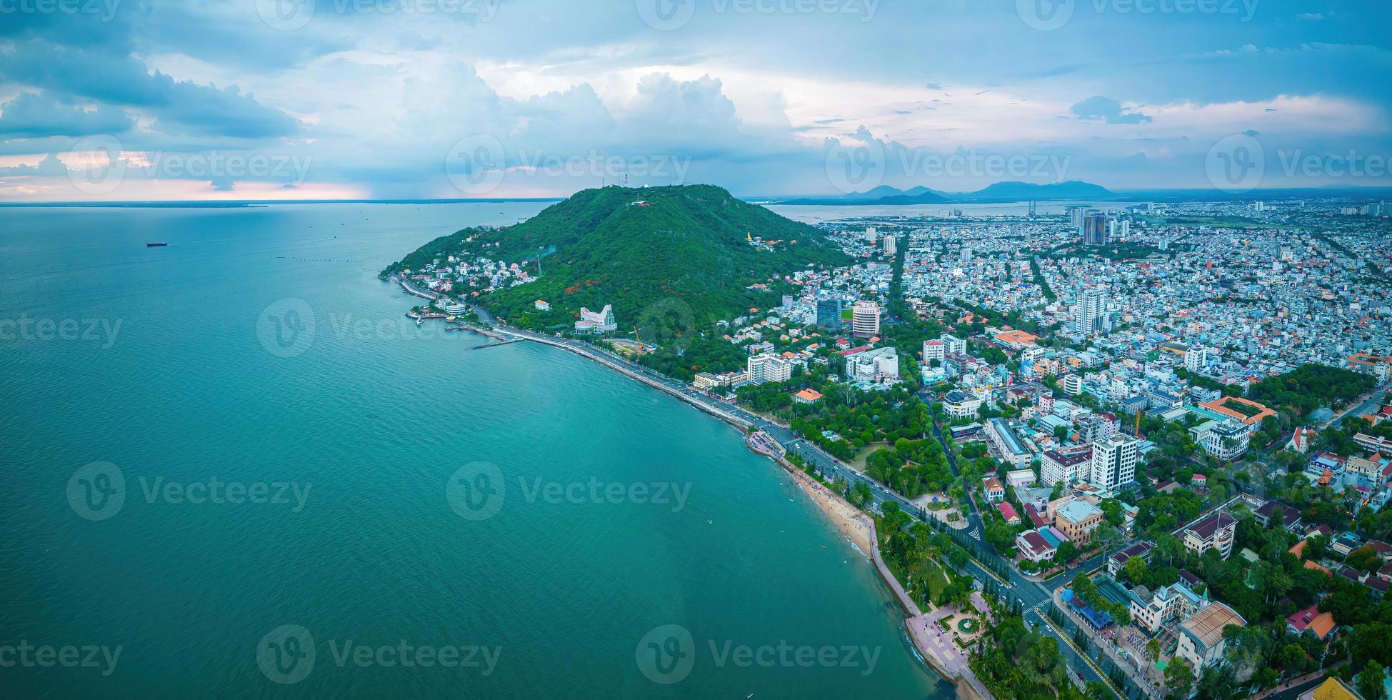 Vung Tau city aerial view with beautiful sunset and so many boats. Panoramic coastal Vung Tau view from above, with waves, coastline, streets, coconut trees and Tao Phung mountain in Vietnam. photo
