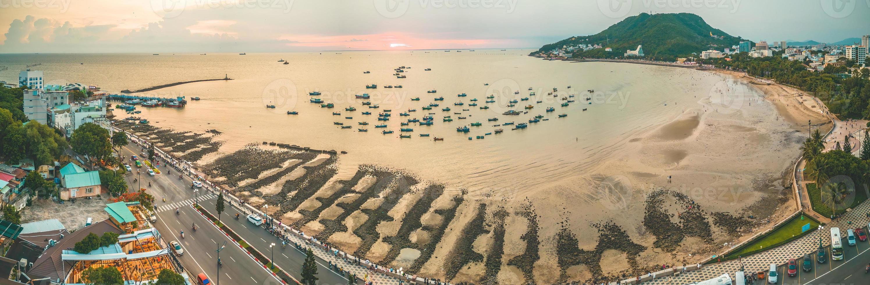 Vung Tau city aerial view with beautiful sunset and so many boats. Panoramic coastal Vung Tau view from above, with waves, coastline, streets, coconut trees and Tao Phung mountain in Vietnam. photo
