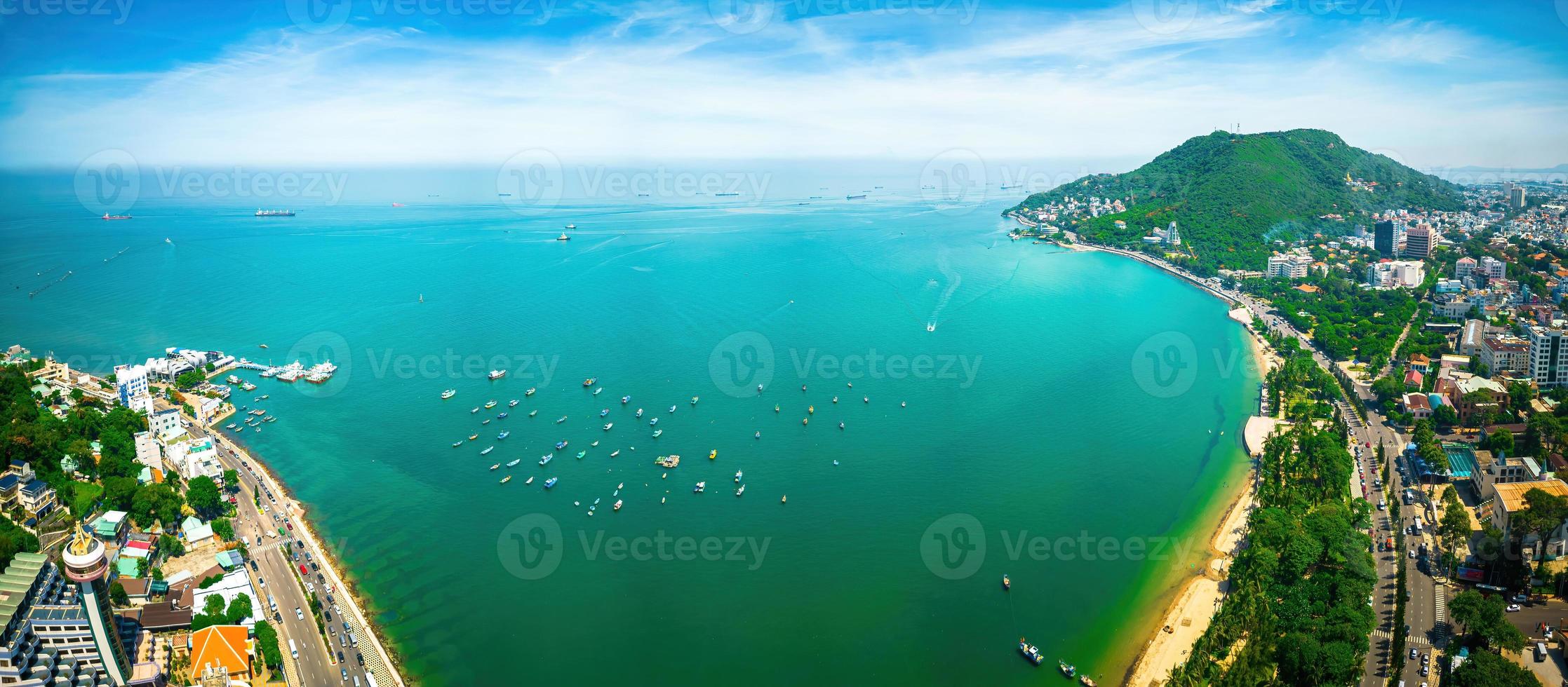 Vung Tau city aerial view with beautiful sunset and so many boats. Panoramic coastal Vung Tau view from above, with waves, coastline, streets, coconut trees and Tao Phung mountain in Vietnam. photo