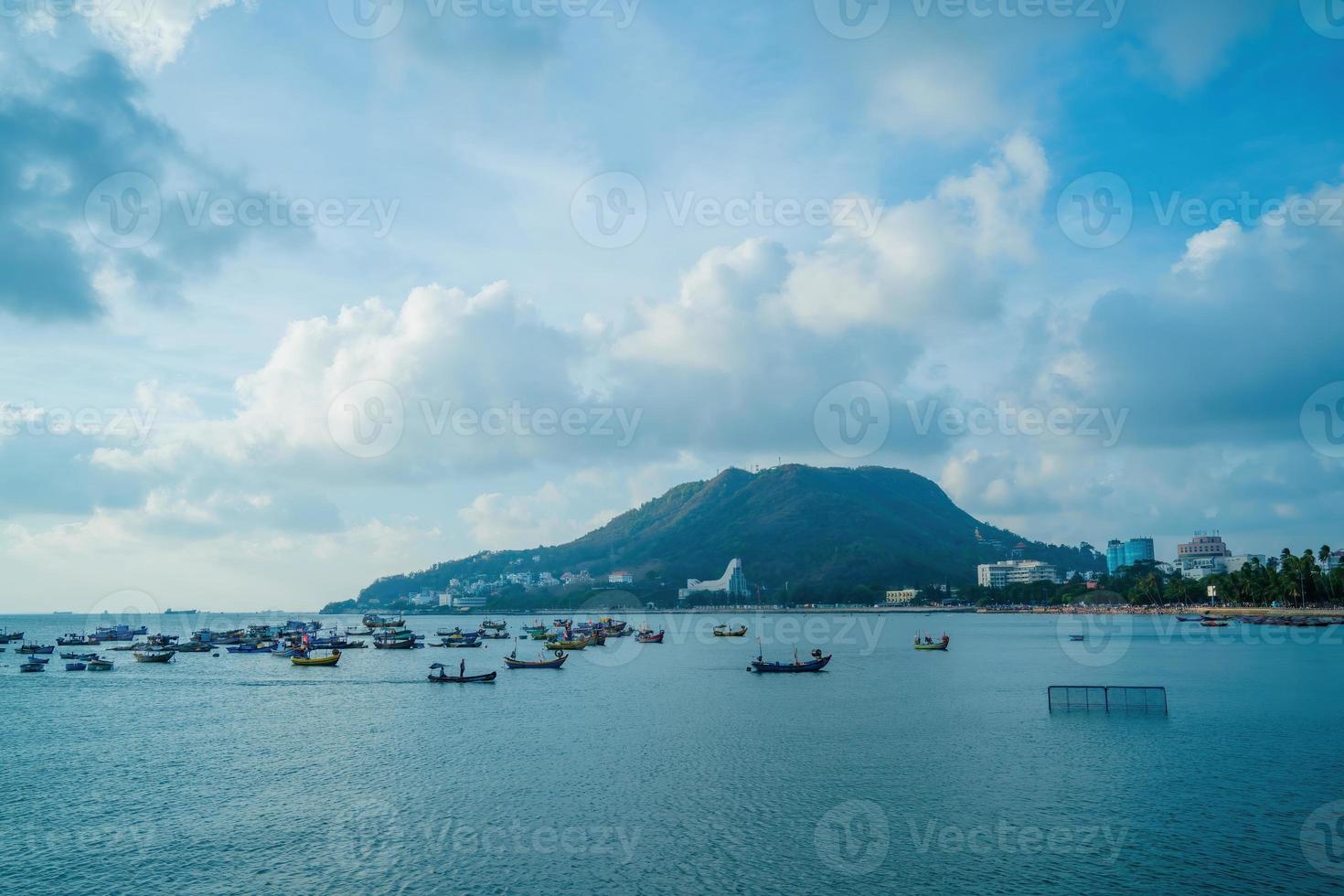 Vung Tau city aerial view with beautiful sunset and so many boats. Panoramic coastal Vung Tau view from above, with waves, coastline, streets, coconut trees and Tao Phung mountain in Vietnam. photo