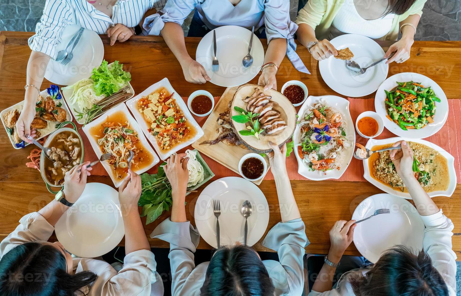 Topview of Thai local food such as Somtum papaya spicy salad, grilled pork, tomyum, vegetable and shrimp curry are arranged on wood table. photo