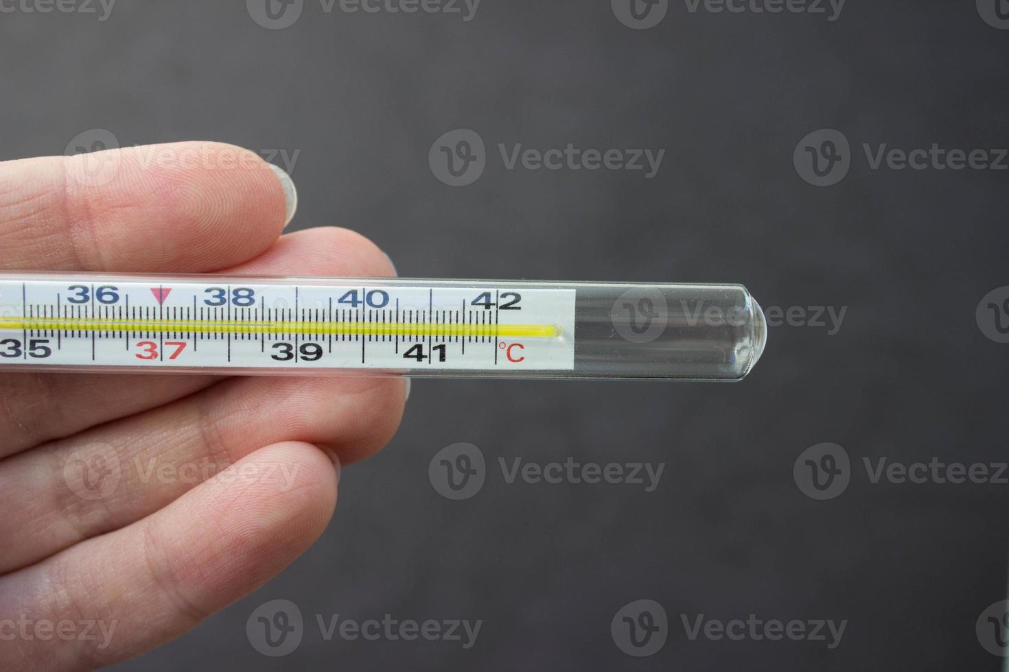 Mercury thermometer in hand on black background. Close up photo