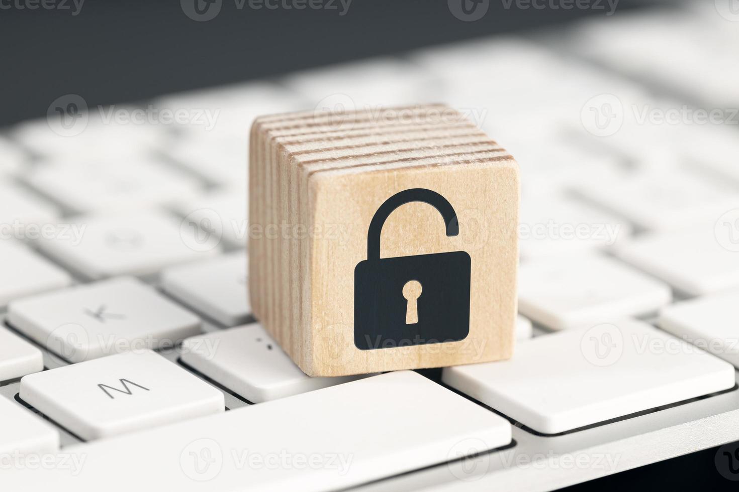 Computer security risk concept. Open padlock icon on wooden cube on computer keyboard photo