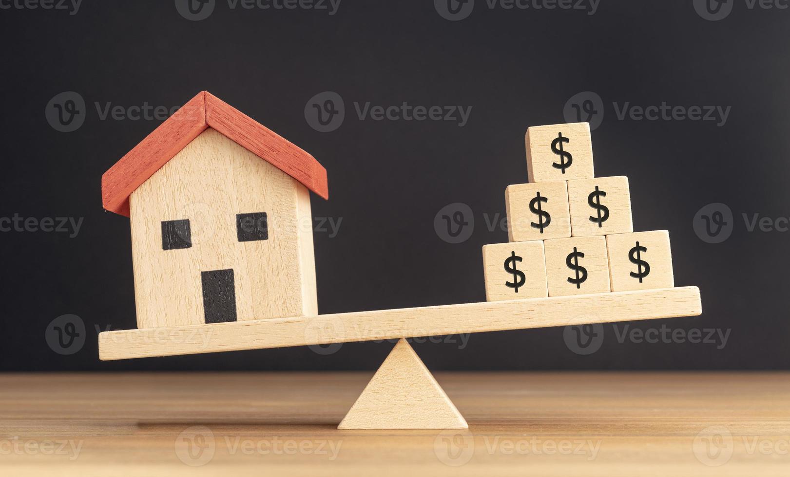 House or Property investment concept. House model and wooden blocks with dollar sign balancing on a seesaw photo