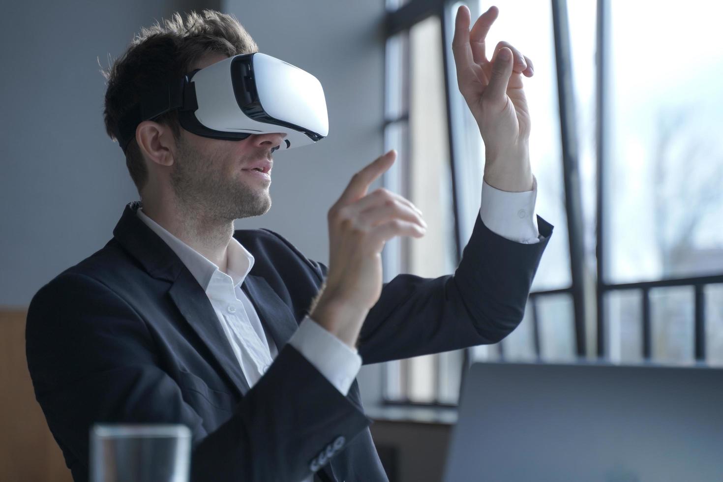 Excited man office worker wearing vr goggles touching objects with hands in digital world photo
