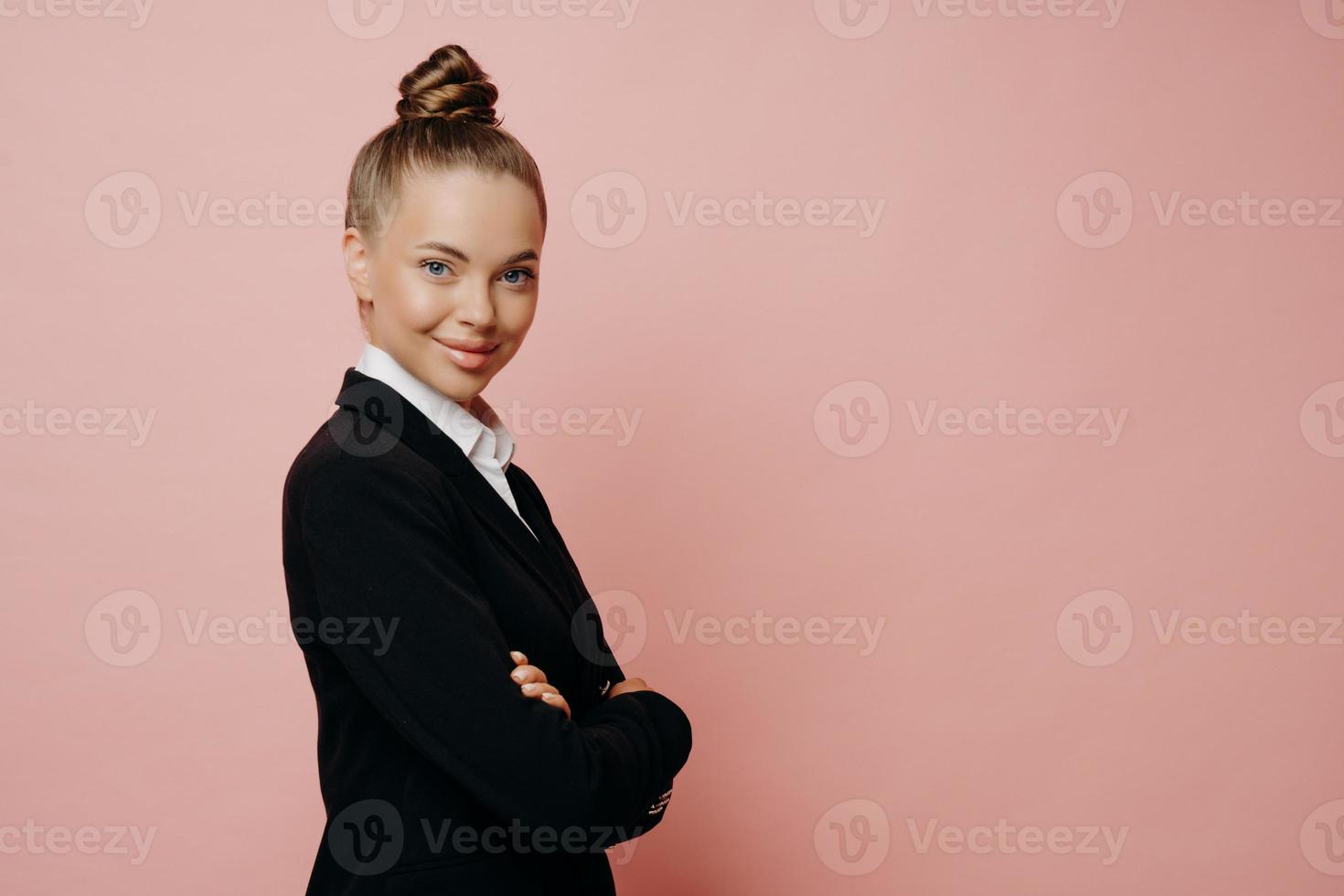 Confident business lady keeping arms folded while posing in studio photo