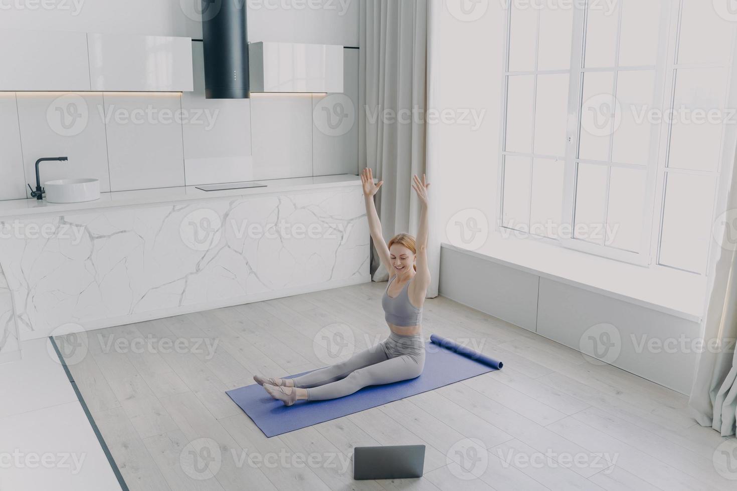 mujer joven está enseñando yoga en video con laptop. concepto de trabajo remoto en cuarentena. foto