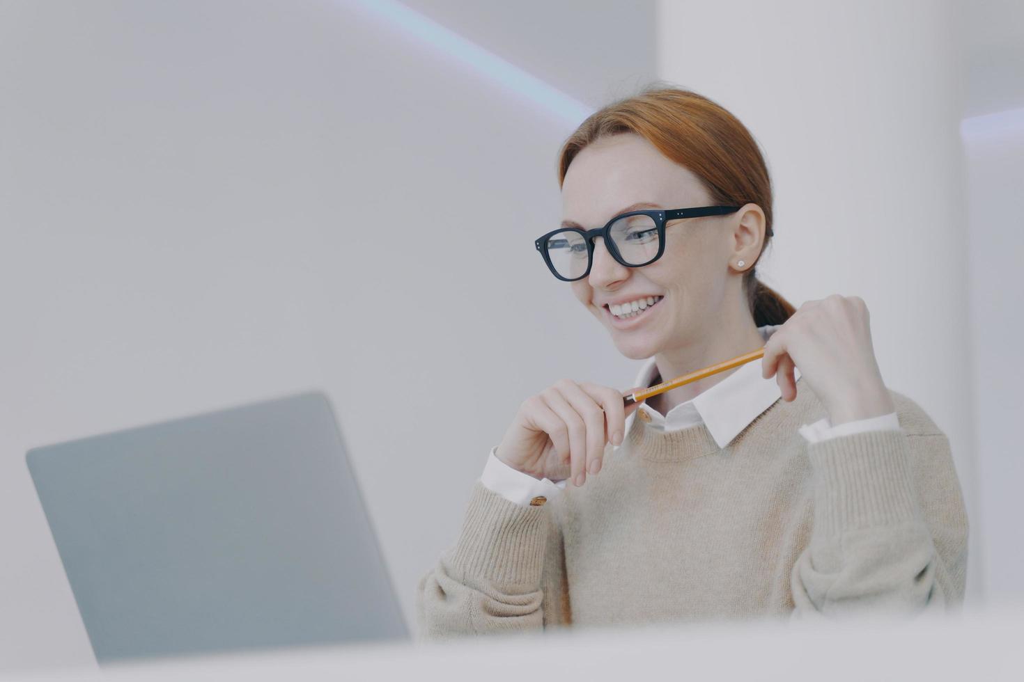 Positive female student. Young european businesswoman in glasses is happy at workplace. photo