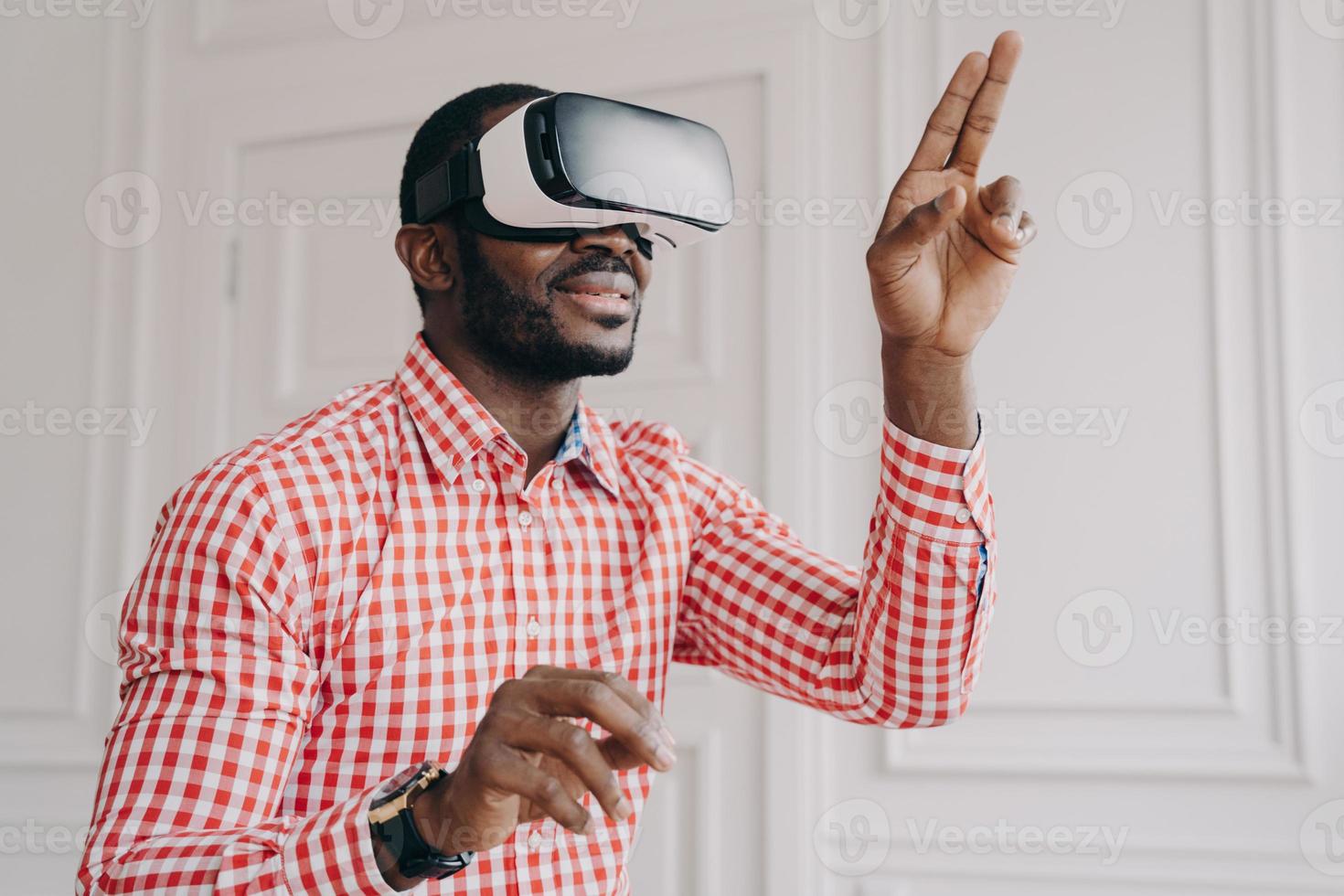 Impressed african ethnicity guy in VR headset glasses enjoying virtual reality online at work photo