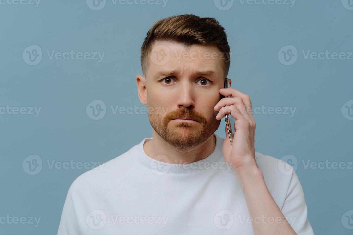 Worried man receiving bad news while talking with somebody on mobile phone photo