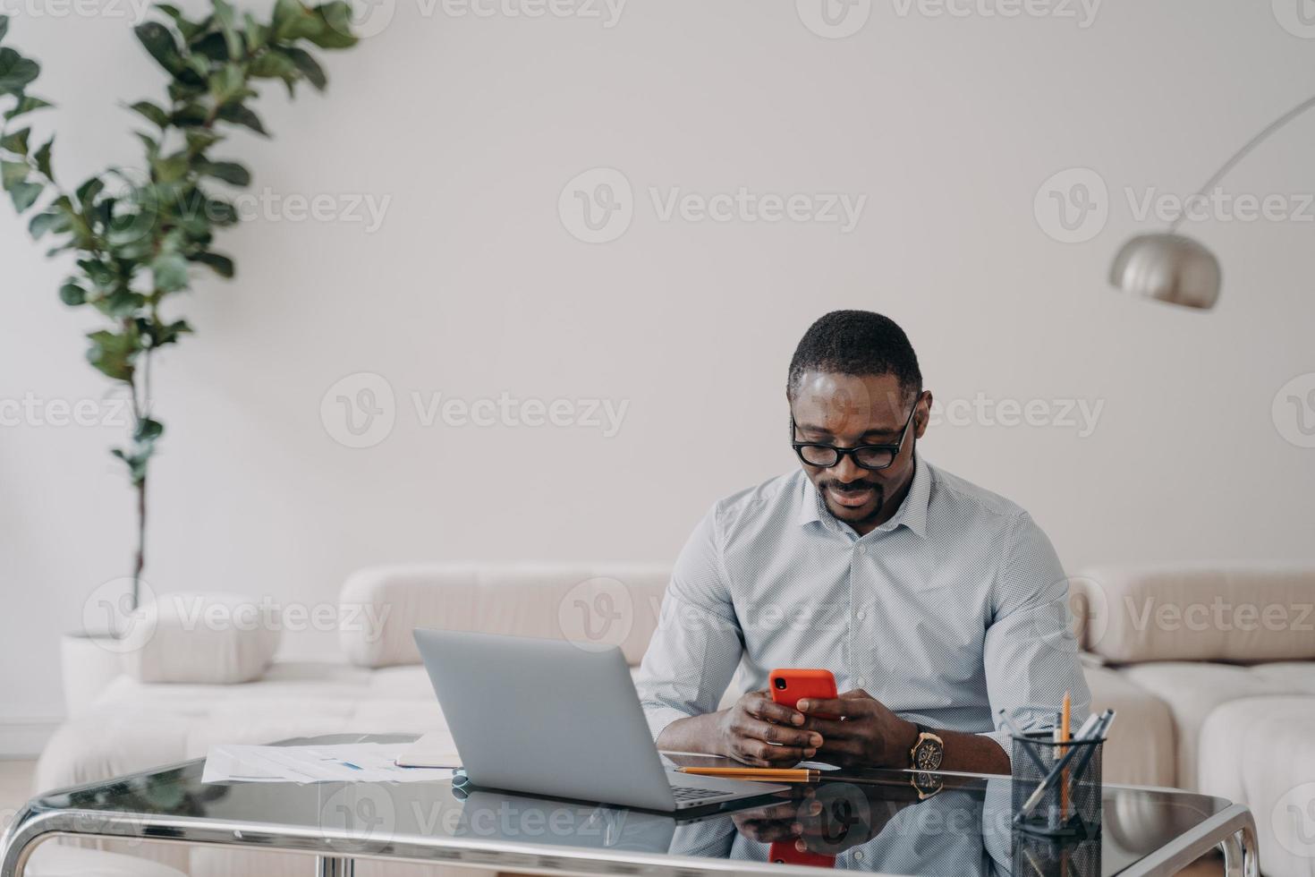 African american businessman uses phone app messages with business partner at office. E-business photo