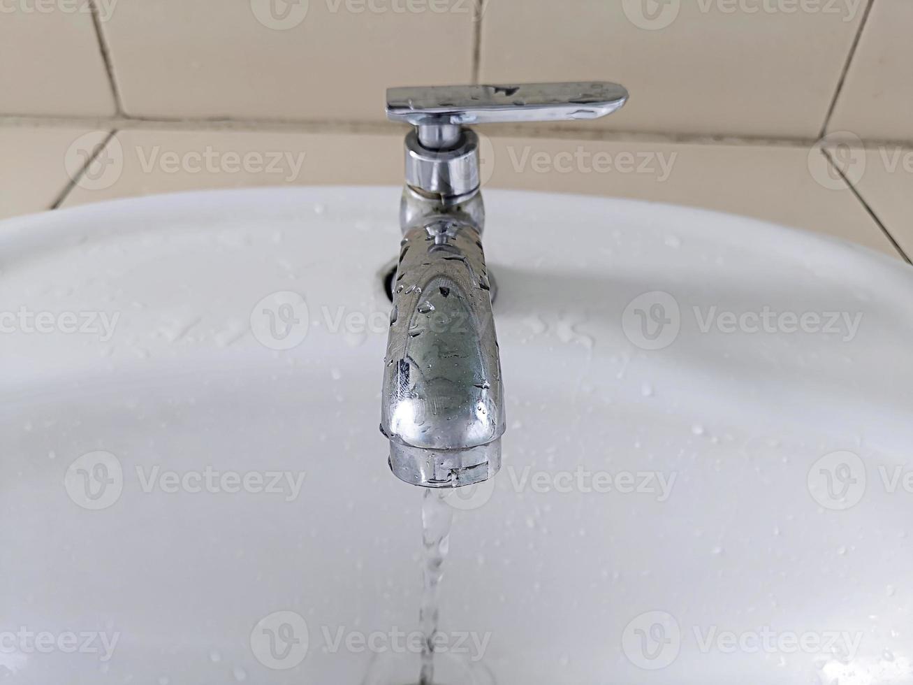 Open faucet in bathroom, water is running photo