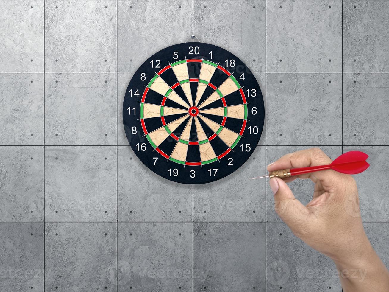 hand holding darts arrow. target for Darts. Concrete wall background. concept marketing target photo