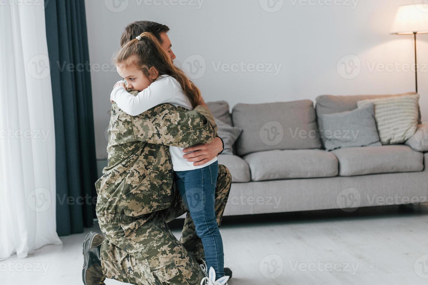 Finally meet each other. Soldier in uniform is at home with his little daughter photo