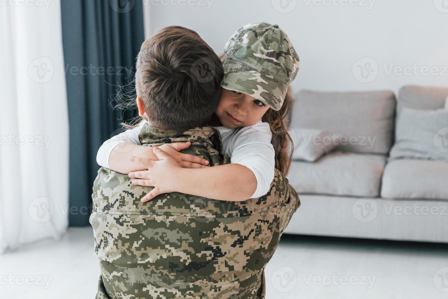 Embracing each other. Soldier in uniform is at home with his little daughter photo