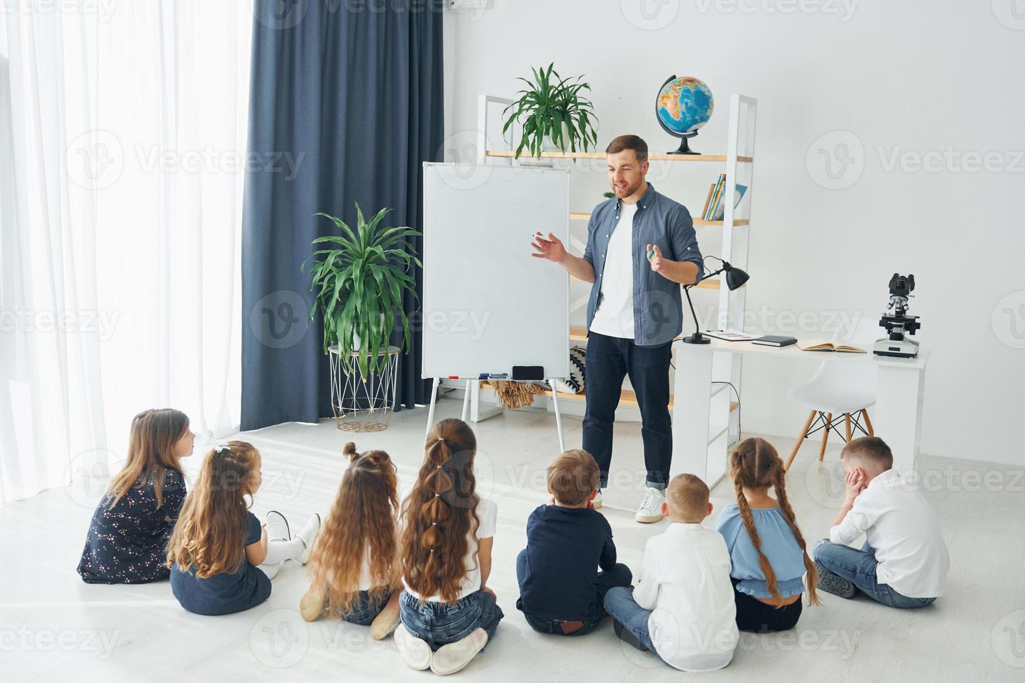 Explaining lesson and using board. Group of children students in class at school with teacher photo