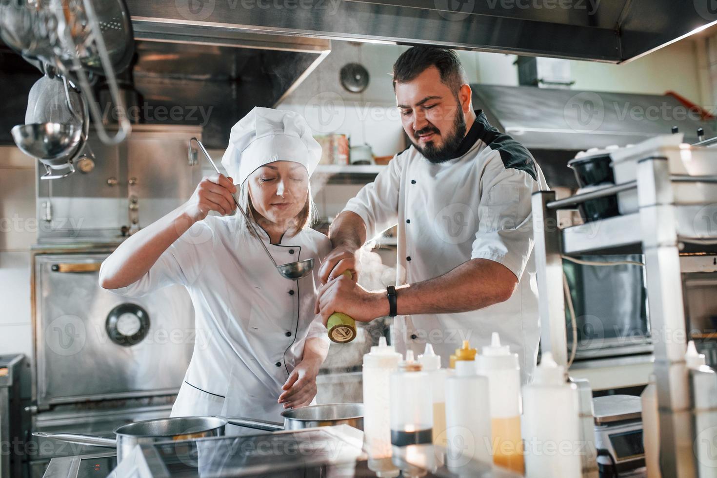 Man and woman cooking meal. Professional chef preparing food in the kitchen photo