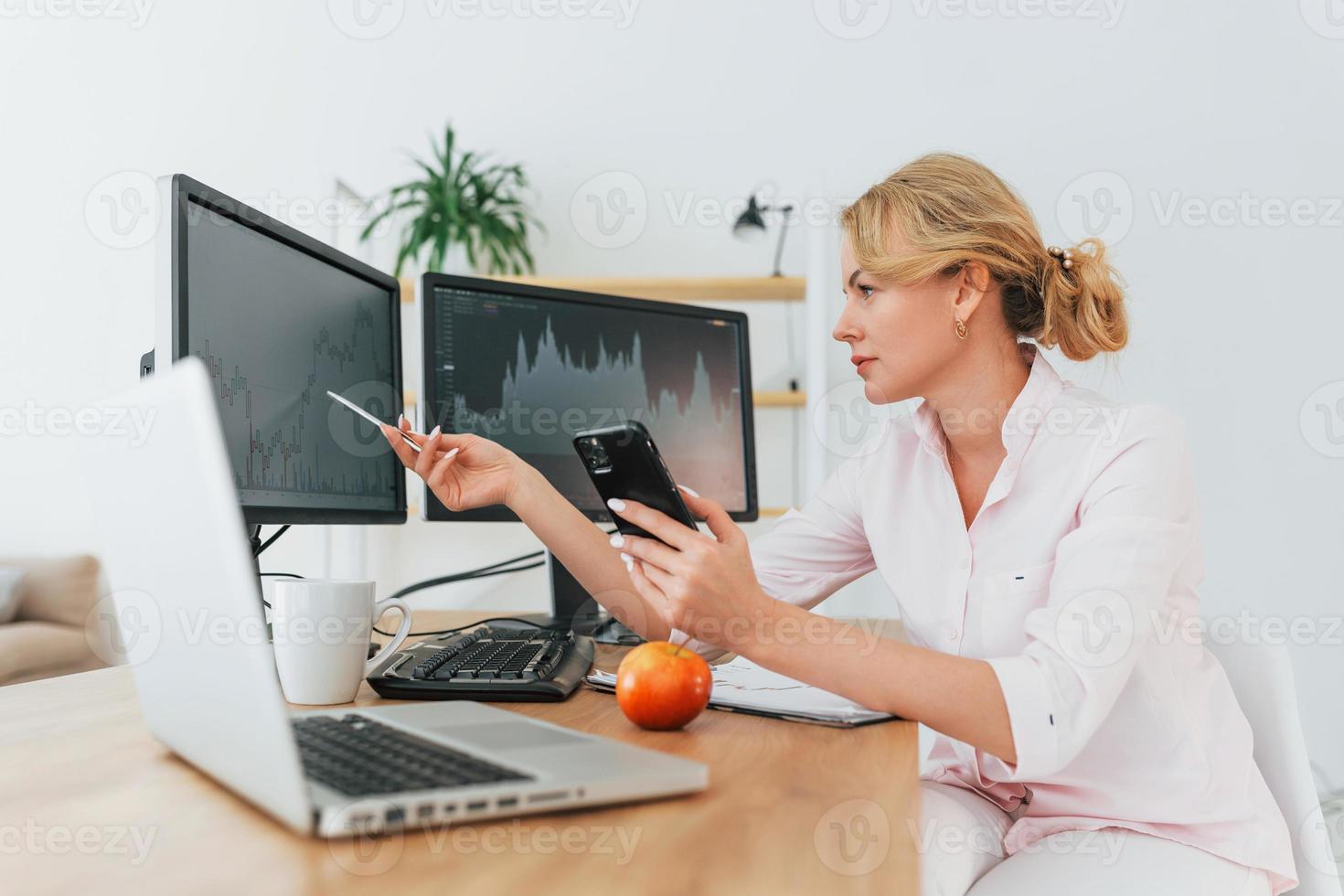 Monitoring the market. Female stock broker in formal wear is working in the office photo