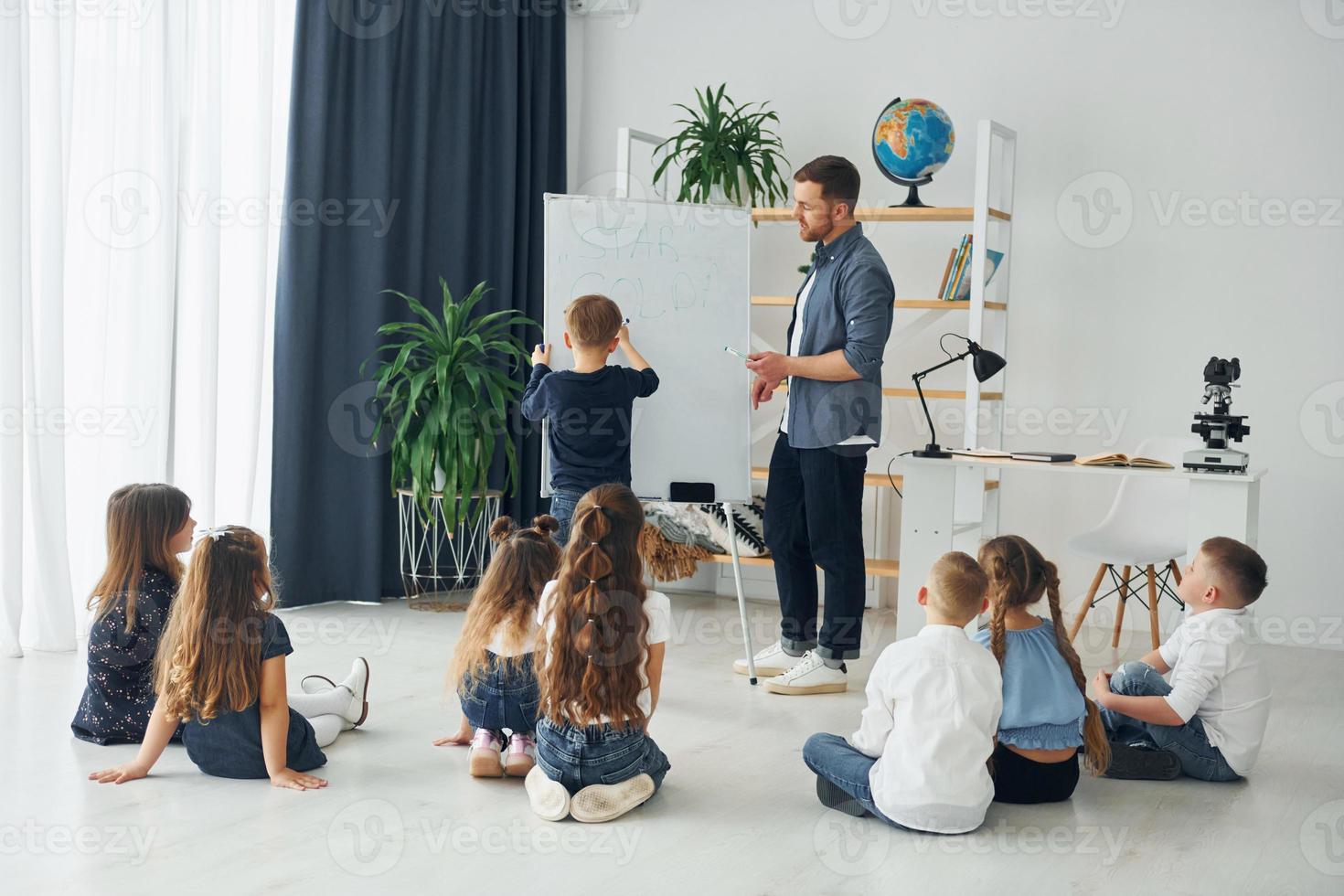 utilizando pizarra. grupo de niños estudiantes en clase en la escuela con el maestro foto