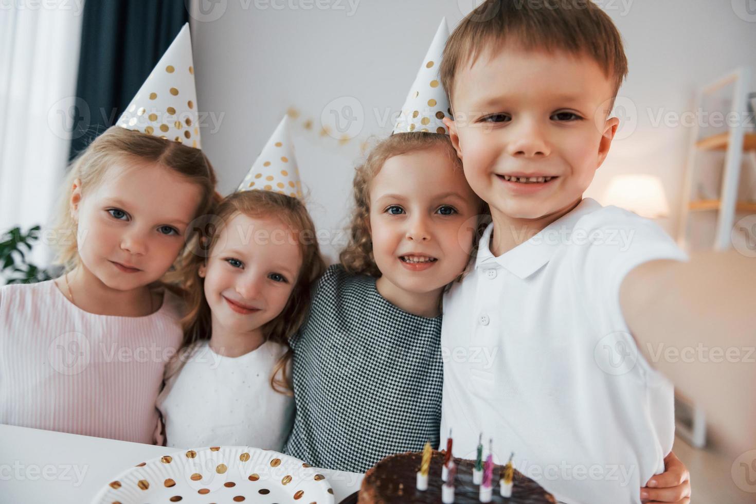 haciendo selfie celebrando el cumpleaños. grupo de niños está juntos en casa durante el día foto