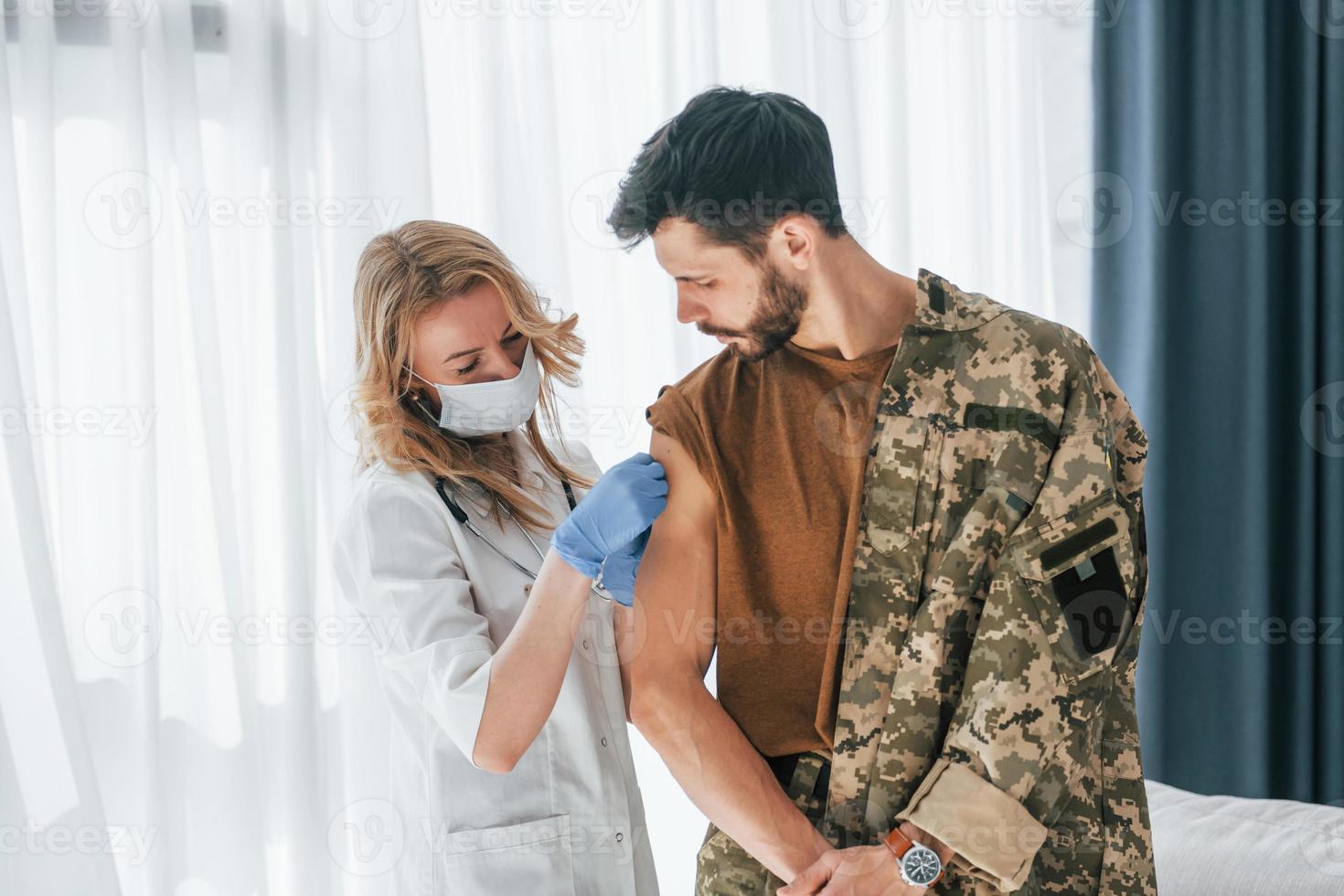 Soldier get vaccinated by female doctor indoors photo