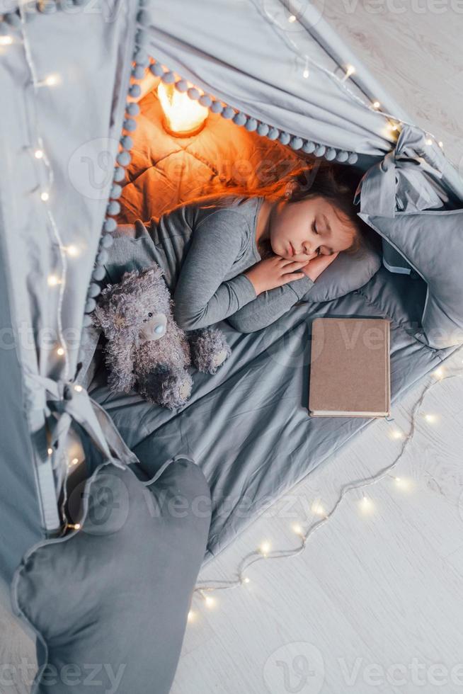 Sleep time. Cute little girl playing in the tent that is in the domestic room photo