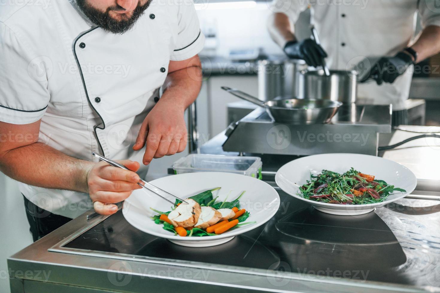 dos hombres están haciendo ensalada. chef profesional preparando comida en la cocina foto