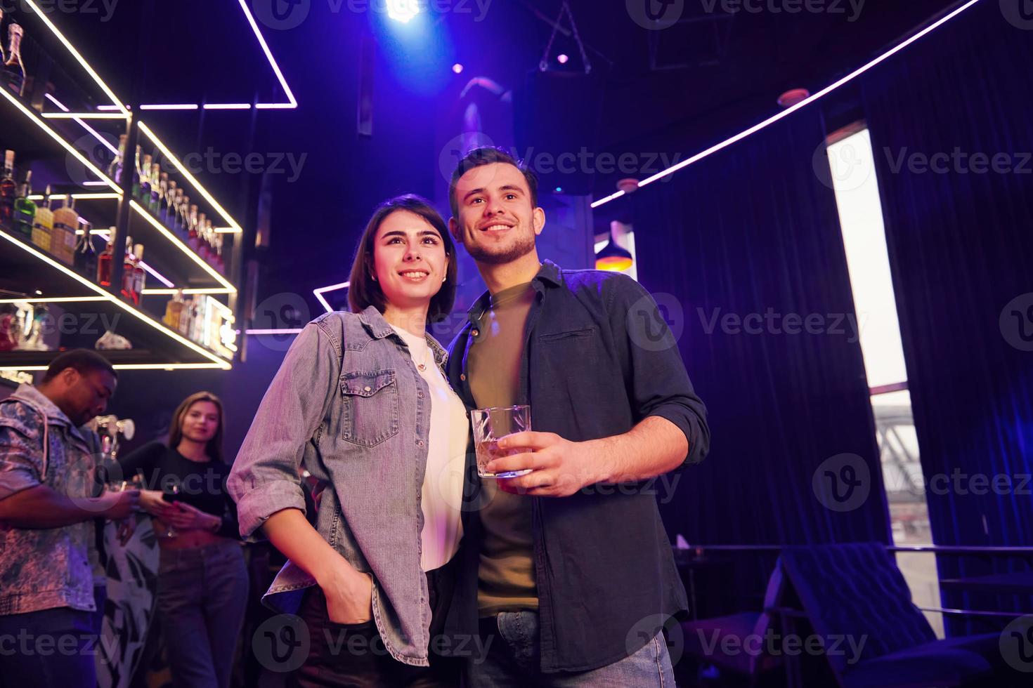 Man with his girlfriend. Group of friends having fun in the night club together photo